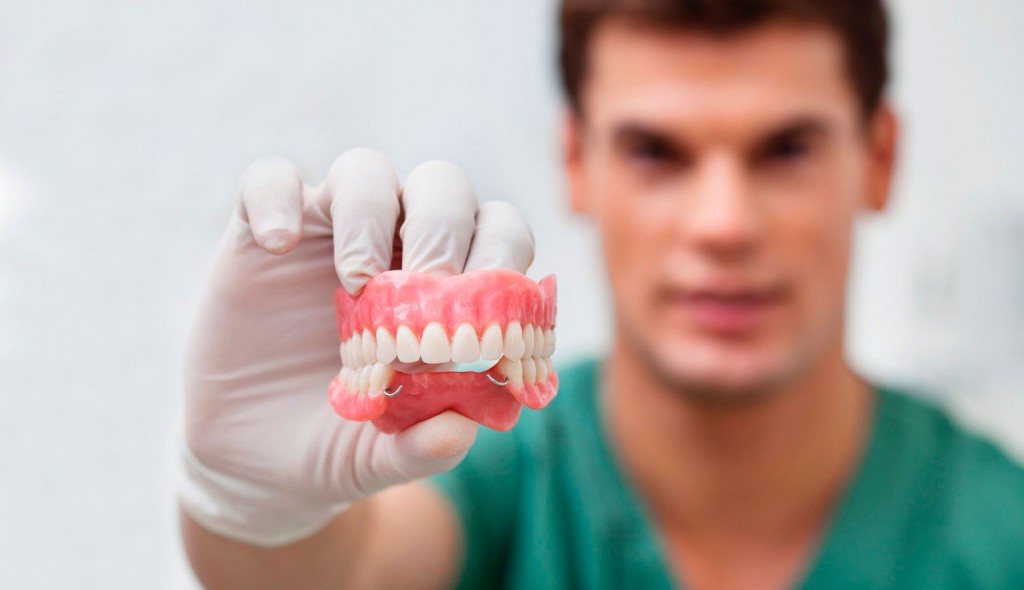 Dentista a mostrar uma prótese dentária